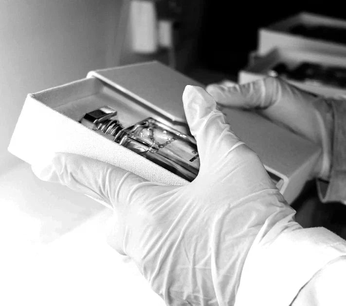 A bottle boxed by gloved hands in the studio