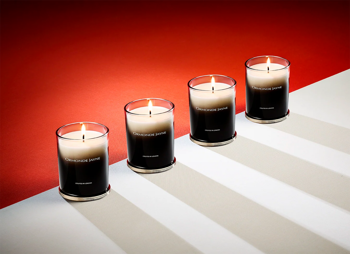 Set of four black and white gradient scented candles in glass holders on red and white surface