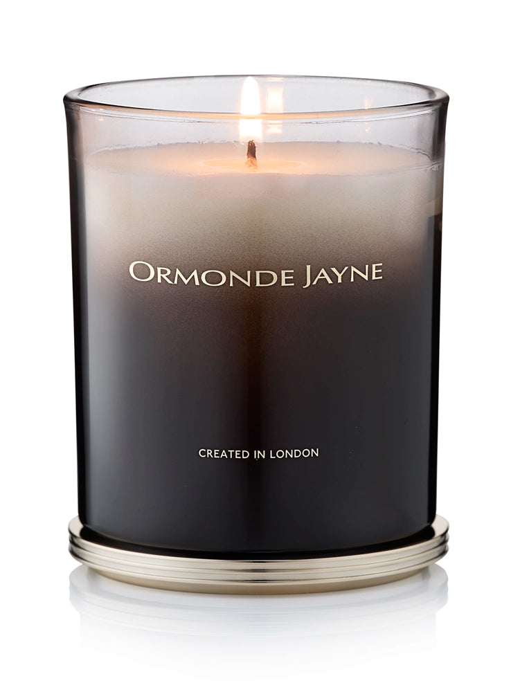 Lit Champaca scented candle in a frosted black glass holder with gold base and lettering