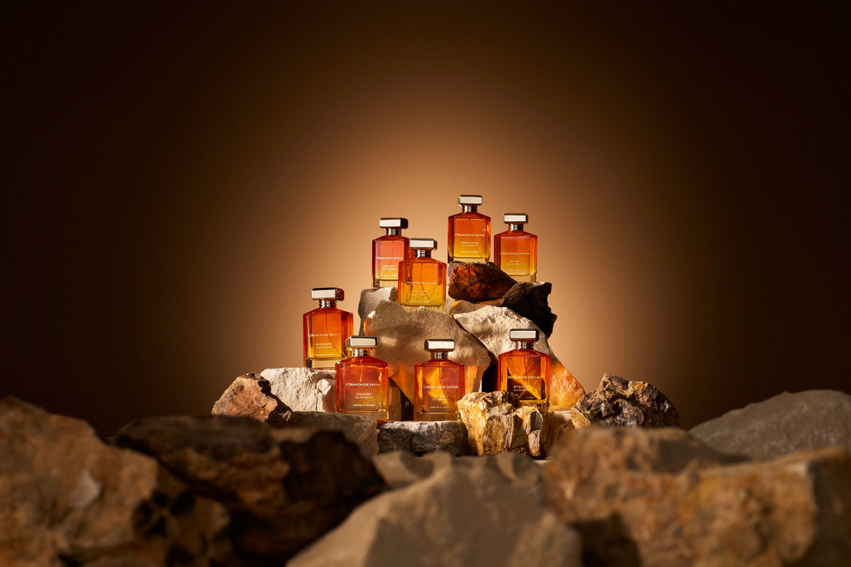 Amber-lit perfume bottles gathered on stone